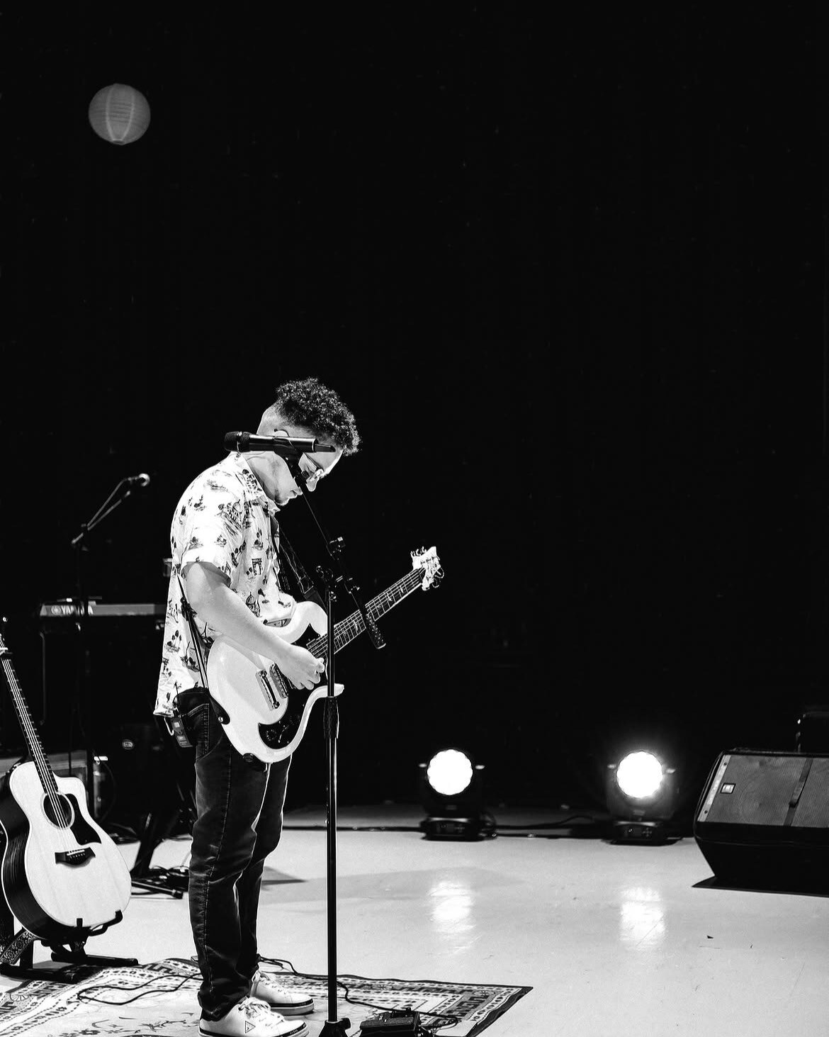 El Científico de perfil en el escenario, con la guitarra acústica al lado